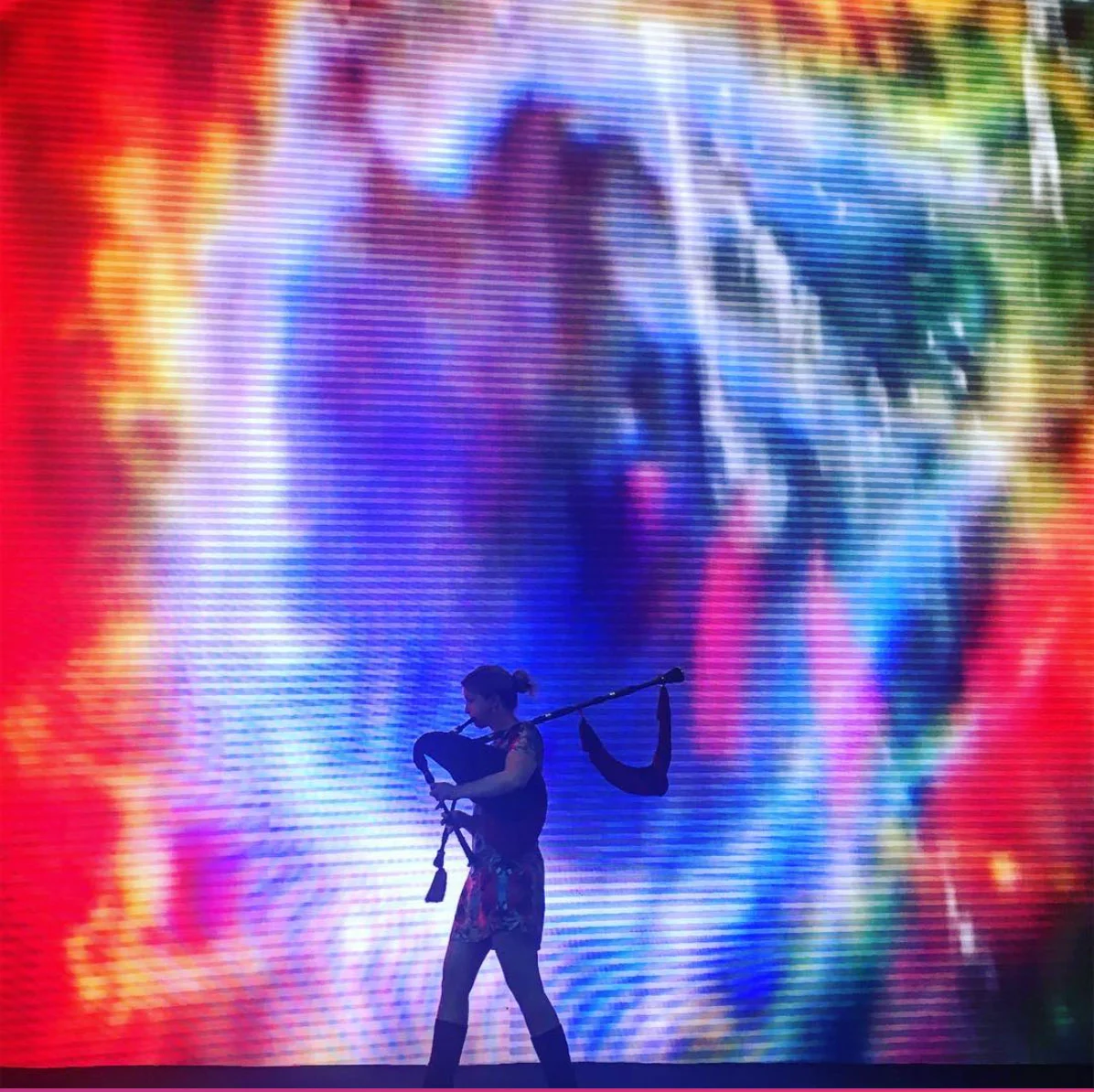 Christine playing gaita in Shenzhen against a vivid projected image